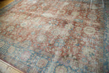 Angled perspective on a distressed vintage Tabriz rug, showing the soft patina over its red and blue palmette design.