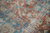 Close-up of celadon red and sky blue palmettes on a distressed vintage Tabriz rug.