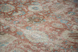 Angled view of the distressed texture on a vintage Tabriz carpet with faded palmettes.