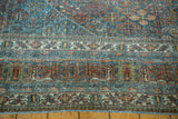 Distressed texture of a vintage Joshegan rug, with intricate sapphire and ruby floral border.