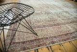 Distressed antique Kermanshah carpet border detail with blush-red motifs, low pile, and visible foundation.