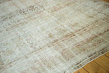 Distressed antique Kermanshah carpet's worn pile, exposed foundation, and soft, faded floral patterns.