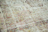 Faded mil fleur motifs and exposed foundation on an antique distressed Kermanshah carpet.