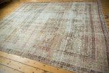 Distressed antique Kermanshah pile showcasing intricate floral and trefoil motifs in faded ivory and raspberry tones.
