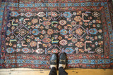 Antique Kurdish rug's dark navy field with tribal Herati pattern, madder red, sky blue borders, with feet.