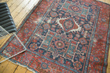 Geometric floral motifs in navy, red, and teal on an antique Karaja rug, showing areas of even wear.