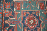 Hand-knotted Heriz style geometric floral patterns in navy, mallard green, and coral.