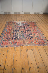 Karaja rug corner with madder root red geometric border, navy blue field, and visible wear.