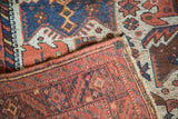 A corner of an antique Afshar rug showing the low pile, secured selvage, and hand-knotted foundation.