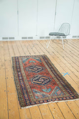 Antique Heriz runner end, madder red field, navy border, intricate motifs, gentle wear, and fringe.