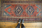 Antique Heriz runner with navy octagonal medallion, brick red field, serrated leaves and pinwheels.