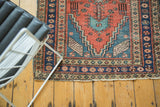 Antique Heriz runner's navy border, floral cross-sections, and secured end.