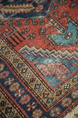 Antique Heriz runner's madder red field, navy border, textured geometric motifs and side cord.