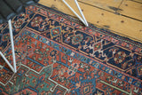Geometric border and rich madder red field of a vintage Karaja rug, showing light tatter.