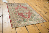 Antique Kaisary Turkish rug's scalloped cherry red medallion, mint green field, and worn pile.