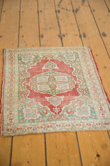 Antique Turkish Kaisary rug corner showing pale cherry red field, mint green motifs, and visible wear.