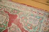 Antique Turkish silk rug displays worn pile, exposed foundation, and faded cherry red design.