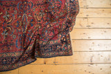 Vintage Lilihan rug's cochineal red field, sprawling palmettes, and navy floral border.
