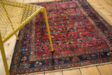 Scrolled palmettes and tendrils in cochineal red and dark navy blue on a vintage Lilihan rug.