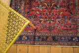 Vintage Lilihan rug's dark navy floral border meeting a cochineal red field with scrolled palmettes.