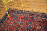 Hand-knotted Lilihan rug corner: cochineal red field, floral tendrils, and dark navy border.