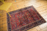 Vintage Lilihan rug's dark navy border and cochineal red field with floral tendrils and fringe.