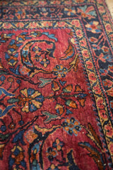 Close-up of Vintage Lilihan rug's cochineal red field, featuring navy and gold curvilinear floral motifs.