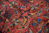 Sprawling cochineal red tendrils, palmettes, and floral motifs with visible wear on vintage Lilihan rug.