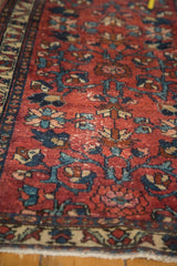 Angled view of vintage Lilihan runner's wine red field, teal floral motifs, and textured pile.