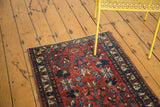 Vintage Lilihan runner in wine red, floral motifs, visible pile recess, with yellow chair legs.