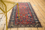 Corner of vintage Lilihan rug featuring wine red floral field and navy border.