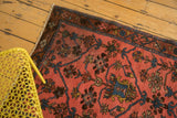 Blush Lilihan rug corner showing ornate tree of life motifs in sky blue and brown.