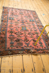 Secured fringed end of the Lilihan rug, with dark blush field and ornate blue pattern.