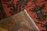 Hand-knotted vintage Lilihan rug folded, showing raspberry pile and striped woven foundation with fringe.