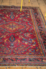 Vintage Lilihan rug detail showcasing raspberry red field, scrolling floral tendrils, and dark navy border.