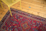 Vintage Lilihan Rug corner: raspberry red field, navy border, palmettes, flowers, and fringe.
