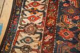 Vintage Malayer rug border featuring geometric patterns in navy, red, and ivory, showing machine binding.