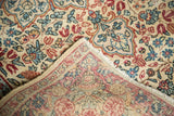 Vintage Kerman rug corner, revealing hand-knotted back, secured edge, and allover mil fleur pattern.