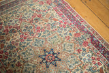 Vintage Kerman mil fleur rug with ivory, cochineal red, blue floral motifs, and visible knot wear.