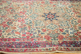 Ivory mil fleur field with blooming roses and worn red border of a vintage Kerman rug.