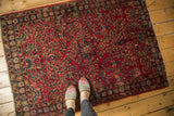 Vintage Lilihan rug corner displaying cherry red field and navy border with floral bouquets.