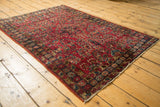 Vintage Lilihan rug corner: cherry red field, intricate floral bouquets, visible wear, navy border.