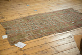 Antique Kurdish rug fragment with a mir boteh pattern, showing its frayed edges and storied threadbare wear.