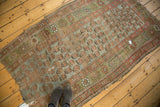 The threadbare and fragmented condition of an antique Kurdish rug in pale slate and sage tones.