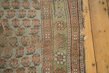 Worn edge of a distressed Kurdish rug, showing threadbare blue mir boteh and geometric borders.