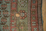 Mir boteh pattern with threadbare texture and prominent hole on antique Kurdish rug fragment.