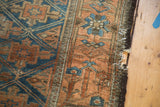 Detail of the antique Belouch rug's distressed perimeter, with sapphire blue geometric guls on terra cotta.