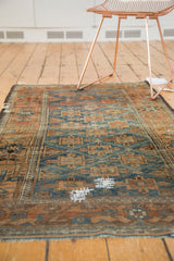 Distressed antique Belouch rug, sapphire blue geometric guls, terra cotta details, and visible hand stitches.