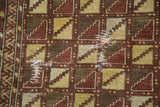 Visible hand-woven repairs on antique Belouch rug's geometric pattern.