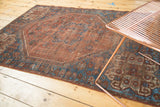 Rug corner showing dark brick red field and sapphire blue germinating plant border.